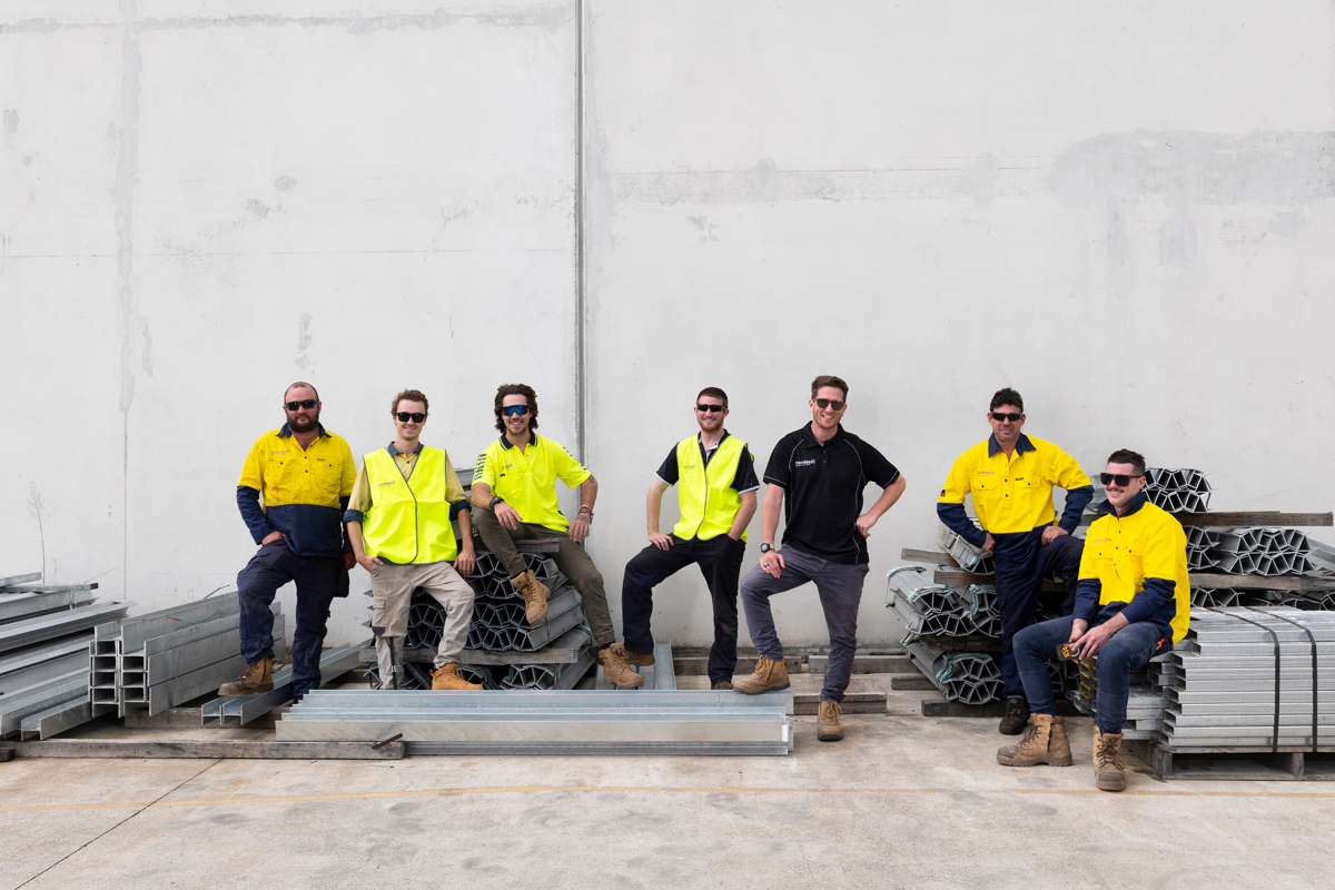 friendly-team-work-male-staff-photo-wearing-hi-vis-clothing-sitting-on-steel-posts